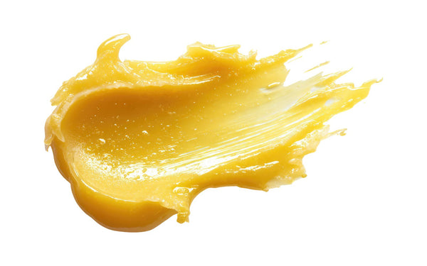 A smear of soft yellow Universal Balm on a white surface, showing its melted, glossy texture