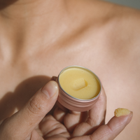 Open 15g tin of Universal Balm held in hand, showing the soft yellow balm texture